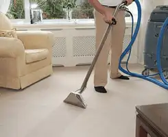 Carpet cleaning professional removing dirt and stains with a hot-water extraction tool in a home, Houston, TX.