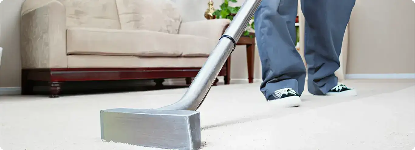 Carpet cleaning technician using a hot-water extraction wand on a light-colored carpet in a living room, Houston, TX.