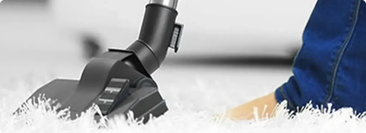 Close-up of a professional vacuuming a white carpet in Channelview.
