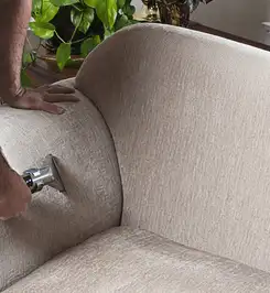 Professional upholstery cleaner deep-cleaning a fabric sofa with a handheld extraction tool and hose Houston, TX.